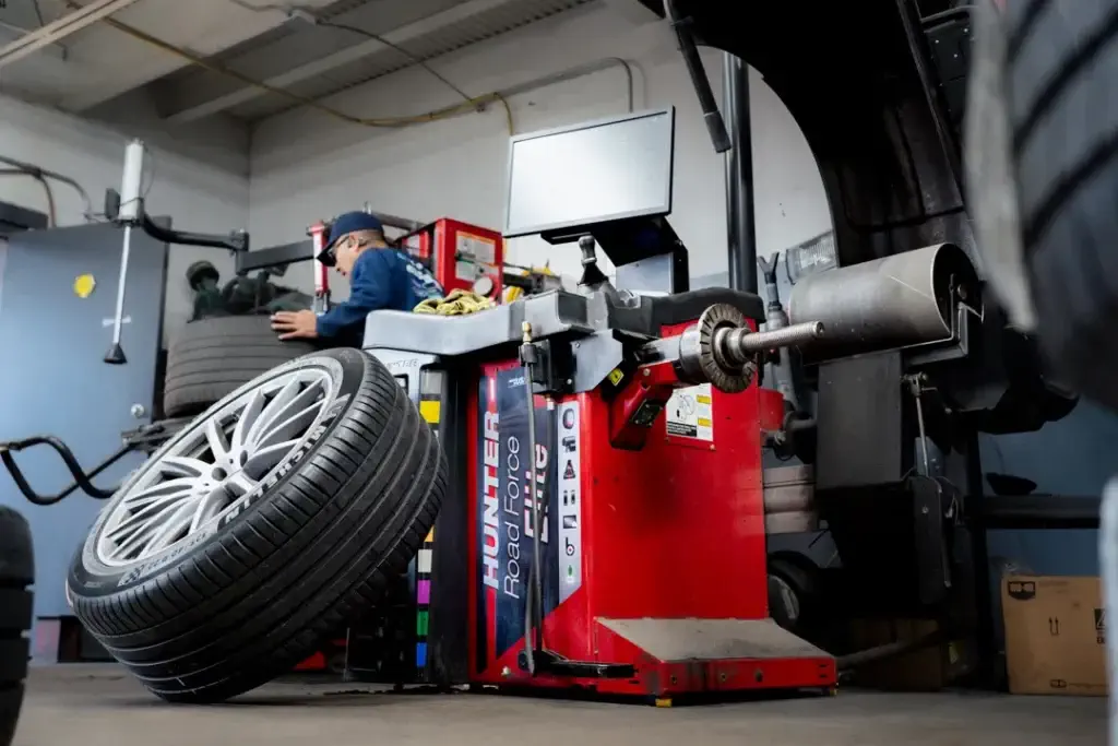 mechanic mounting tire on wheel at auto shop